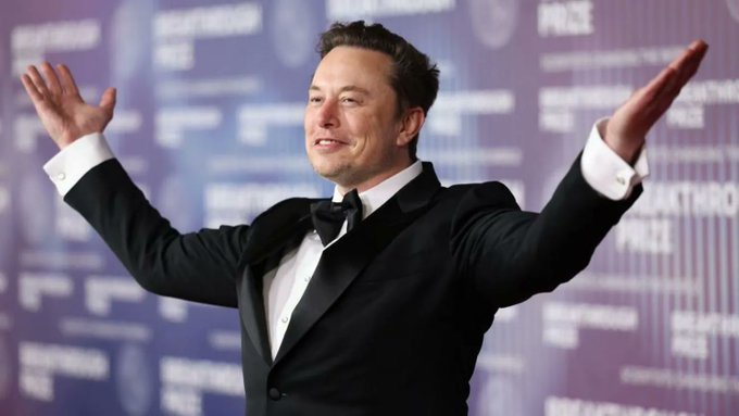 Elon Musk celebrating with arms outstretched in a tuxedo